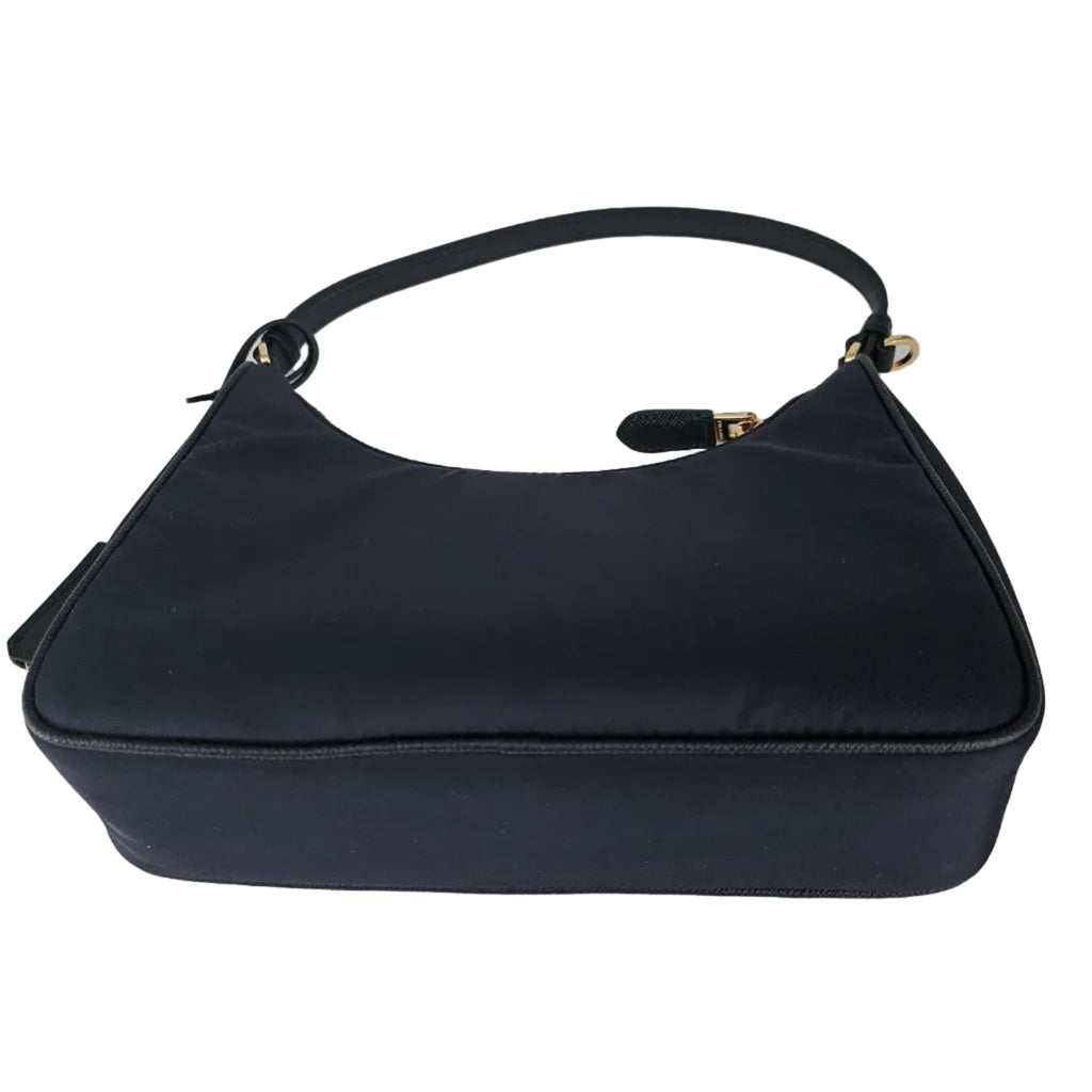 A navy blue nylon shoulder bag with a single strap and gold-tone hardware, photographed against a neutral light gray background.