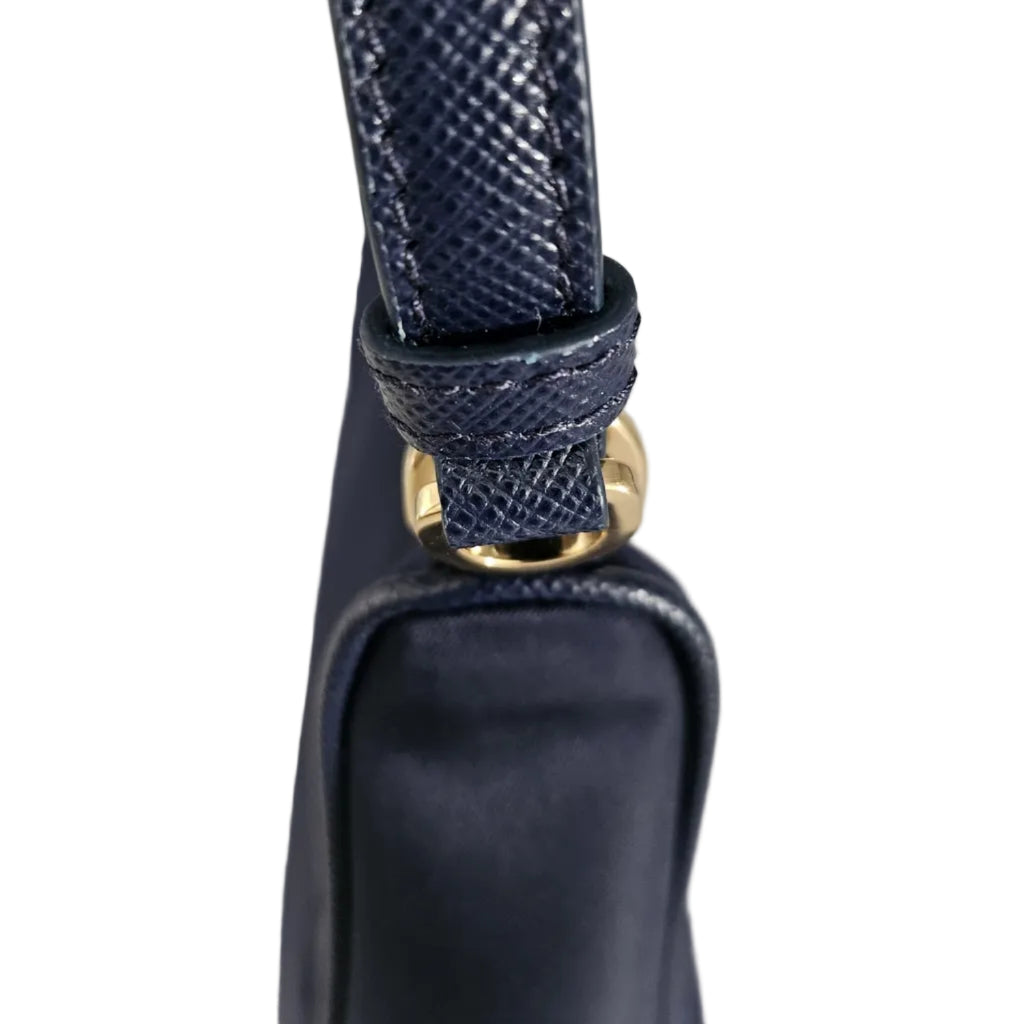 Close-up of a navy blue handbag strap with a textured python-style leather finish and a gold-tone metal ring attachment.