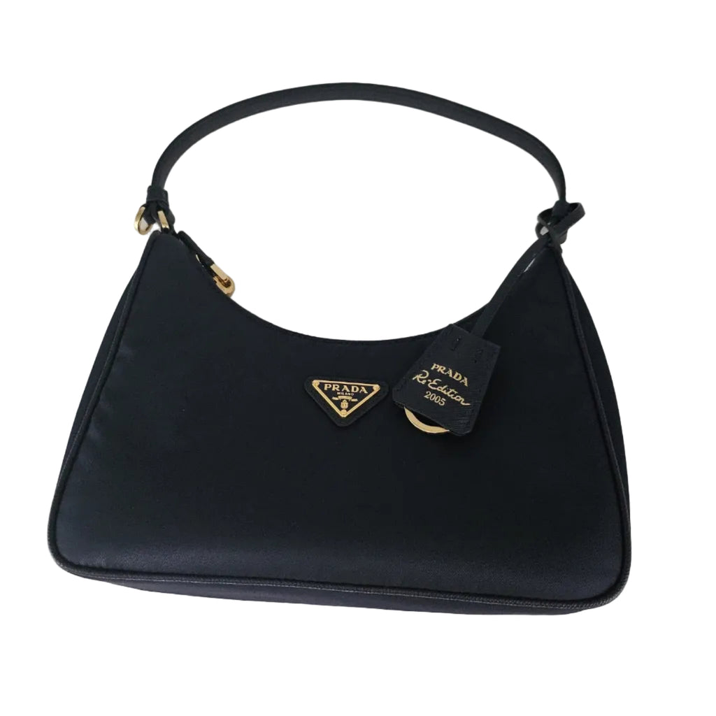 A navy blue Prada shoulder bag made of nylon fabric, featuring a gold-tone triangular Prada logo plaque on the front and a black leather hangtag.