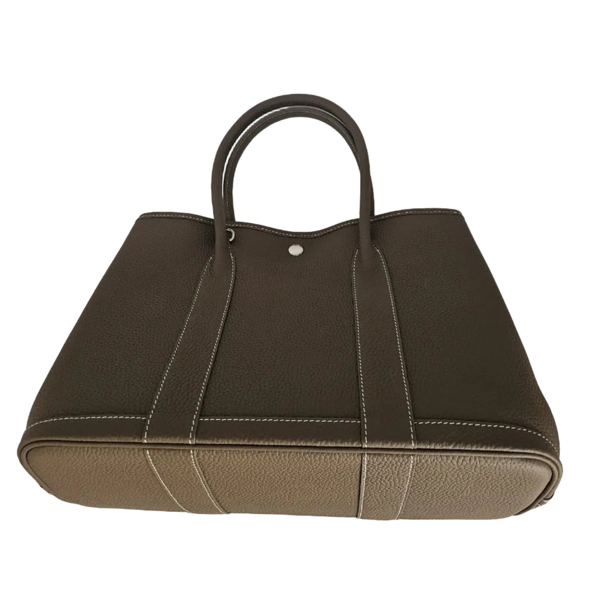 A structured leather tote bag in dark brown and beige, featuring dual top handles, contrast stitching, and a silver-tone snap closure, photographed against a light gray background.